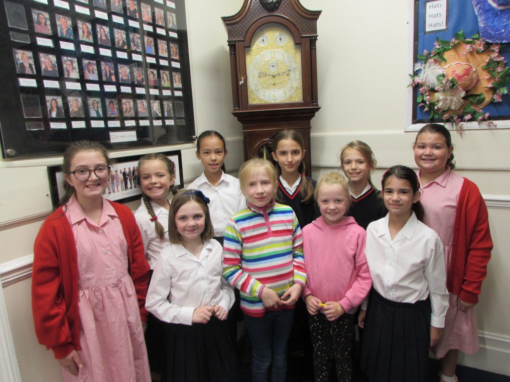 students in a group photo with a grandfather clock in the background