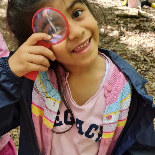 girl holding a magnifying glass to her eye