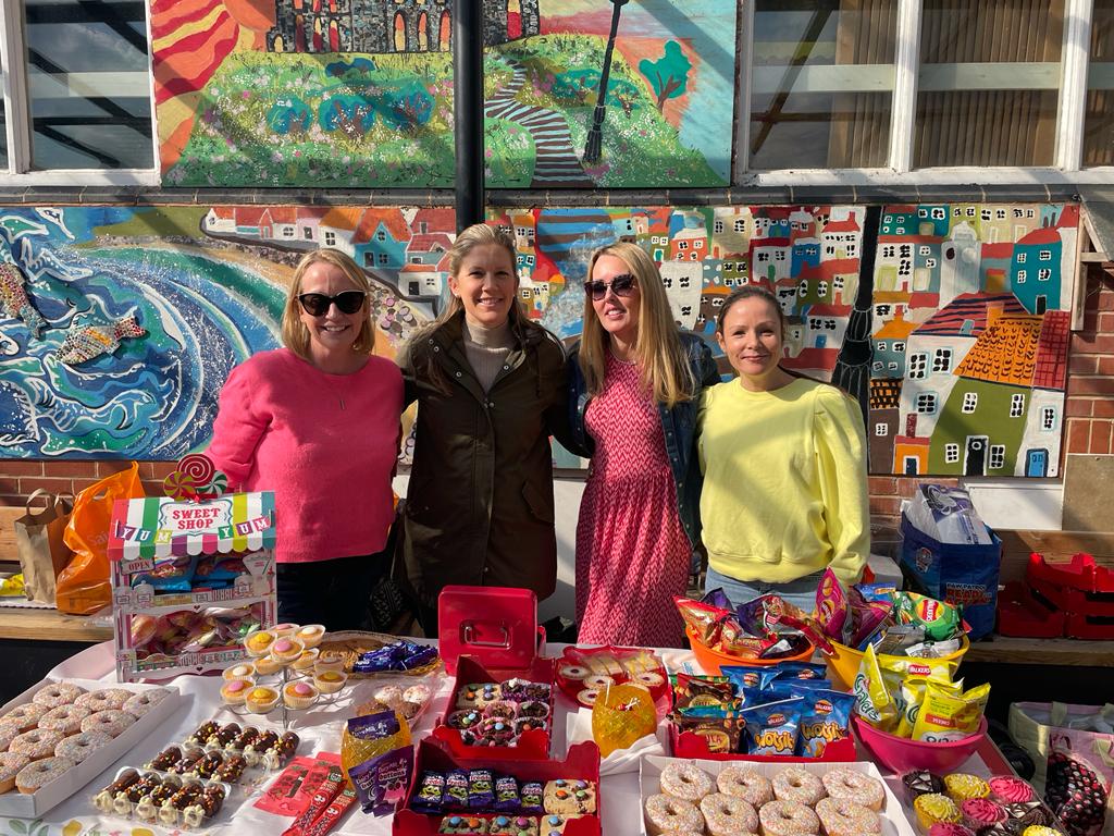 ladies smiling next to a sweets stall