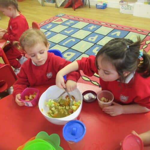 nursery students helping themselves to fruit salad