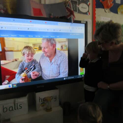 teacher and student watching a boy and his grandad on screen