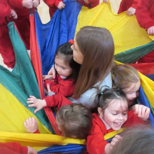 students inside a parachute with their teacher