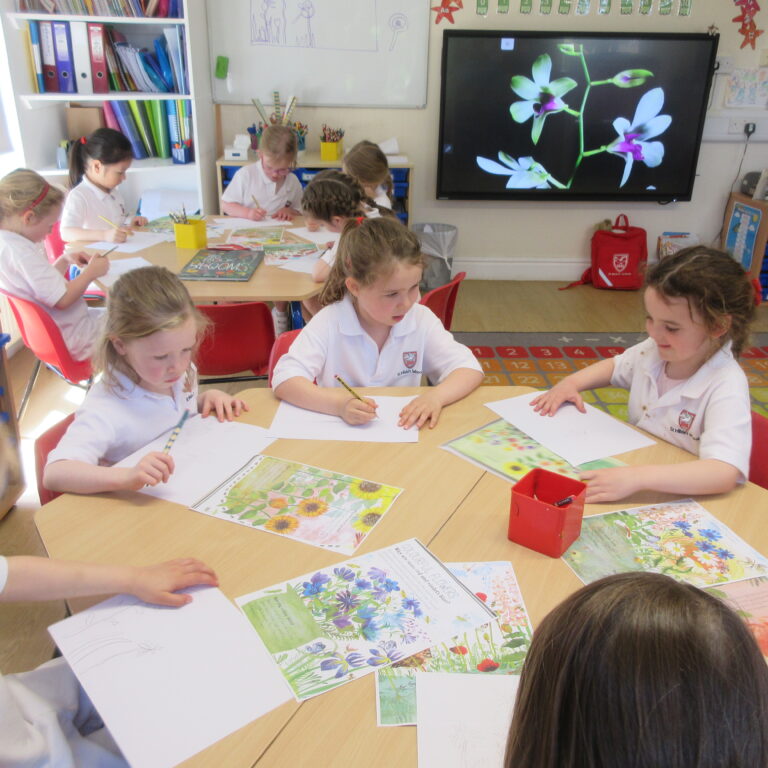 Young students in white uniforms drawing at a table with flower worksheets in a bright classroom.