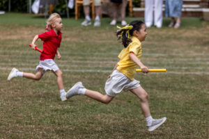 girls in coloured tops running a relay race