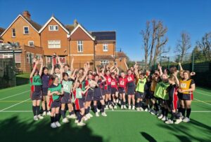 girls on netball court in front of school building in coloured tops