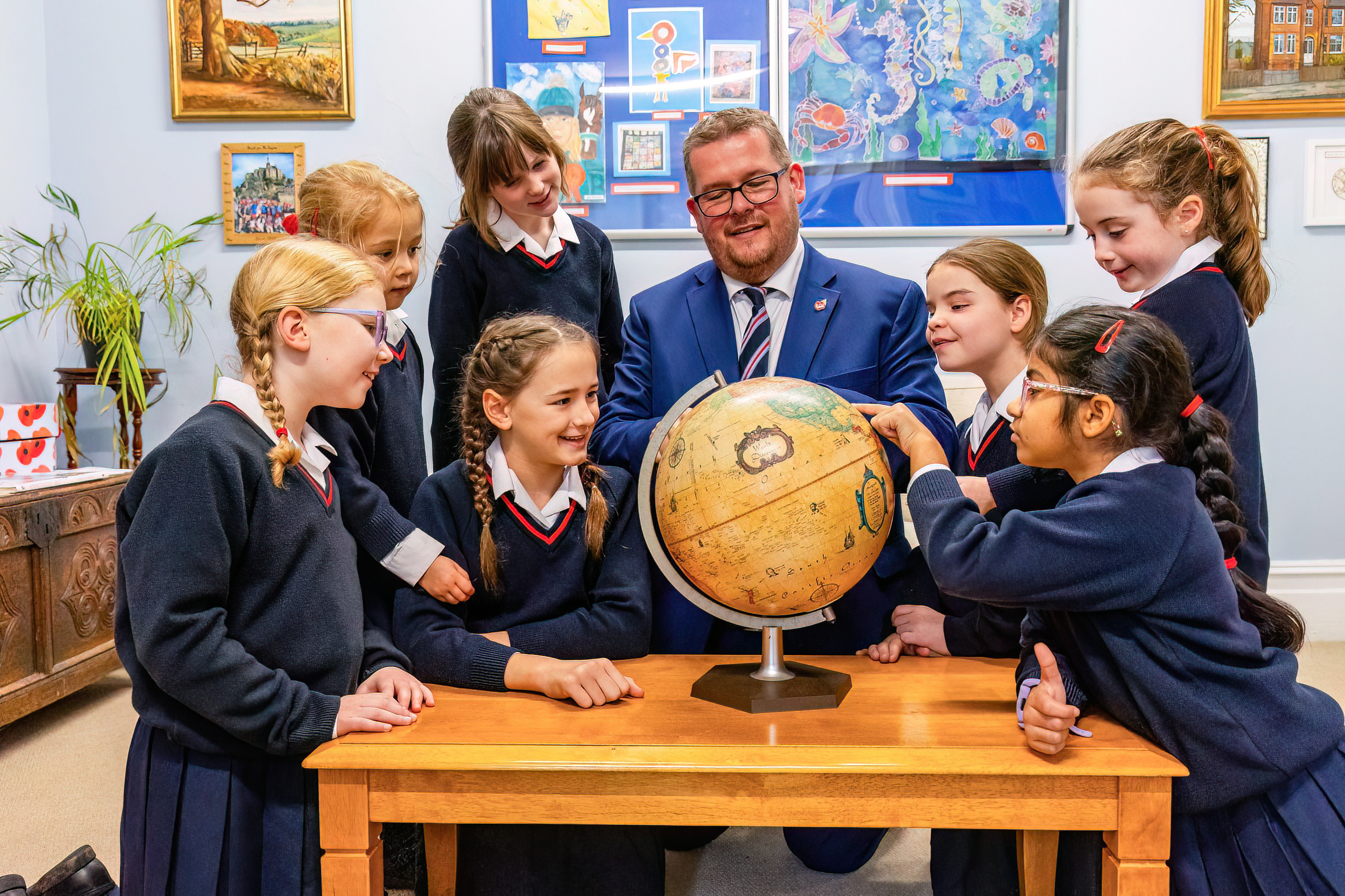 group of students surrounding a globe and their headteacher